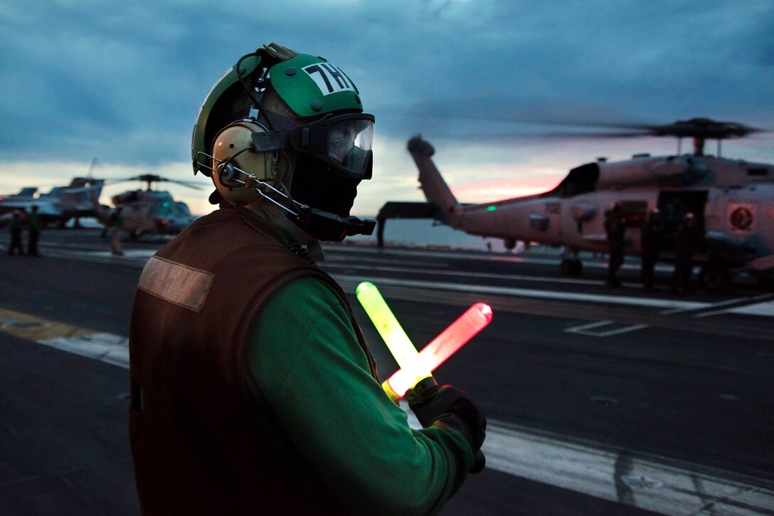 A sailor uses flashlights to direct the crew of an MH-60R Seahawk helicopter on the flight deck of the aircraft carrier USS Carl Vinson in the Pacific Ocean, Jan. 7, 2017. Navy photo by Petty Officer 3rd Class Theo Shively
