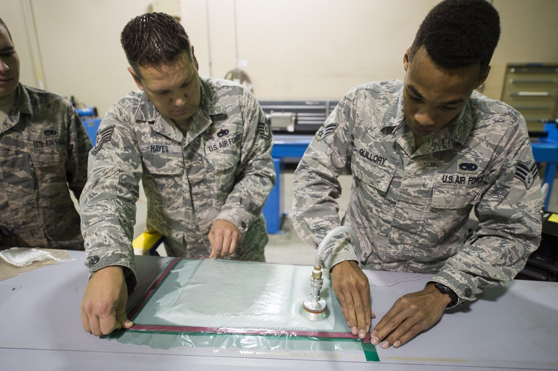 Senior Airman Devon Guillory and Tech. Sgt. Adam Hayes, 49th Maintenance Squadron aircraft structural maintenance technicians, create a seal on a vacuum repair on a composite structure, Dec. 14, 2016, at Holloman Air Force Base, N.M. Once the composite structure is repaired, it can be sanded, painted and returned to the aircraft. (U.S. Air Force photo by Senior Airman Emily Kenney)