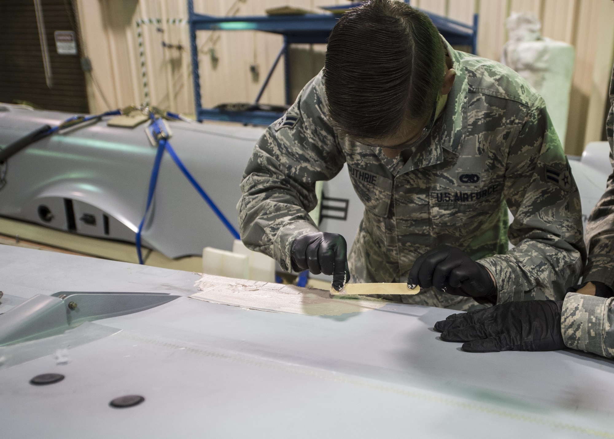 Airman 1st Class Joshua Guthrie, a 49th Maintenance Squadron aircraft structural maintenance technician, applies aircraft smoothing compound to an MQ-1 Predator wing, Dec. 14, 2016, at Holloman Air Force Base, N.M. The sheet metal shop has been prepping an MQ-1 Predator static display for Heritage Park, pending the Predator’s retirement in early 2017. (U.S. Air Force photo by Senior Airman Emily Kenney)