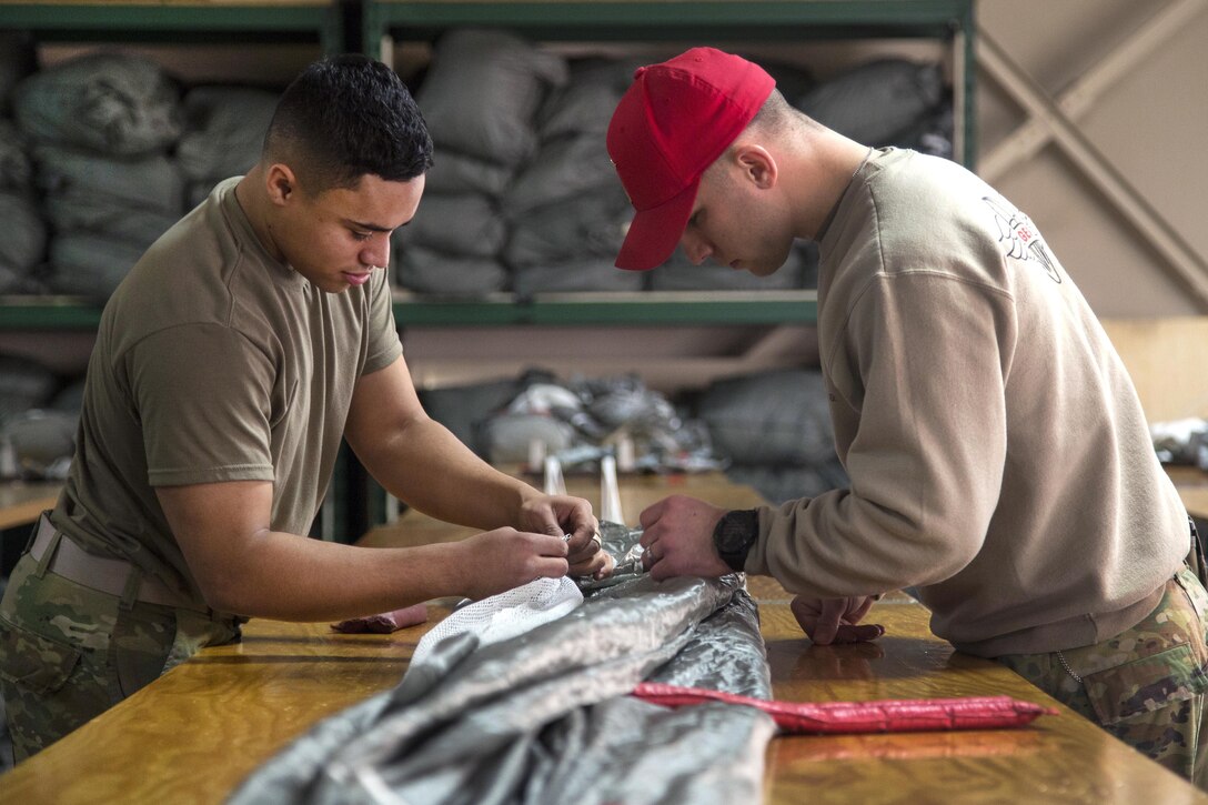 Army Staff Sgt. Nicholas Runyan, right, and Spc. Elisha Gillis inspect a T-11 advanced tactical reserve parachute at Joint Base Elmendorf-Richardson, Alaska, Jan. 4, 2017. Runyan and Gillis are parachute riggers assigned to the 25th Infantry Division’s 4th Quartermaster Company, 725th Brigade Support Battalion, 4th Infantry Brigade Combat Team (Airborne), Alaska. Air Force photo by Alejandro Pena