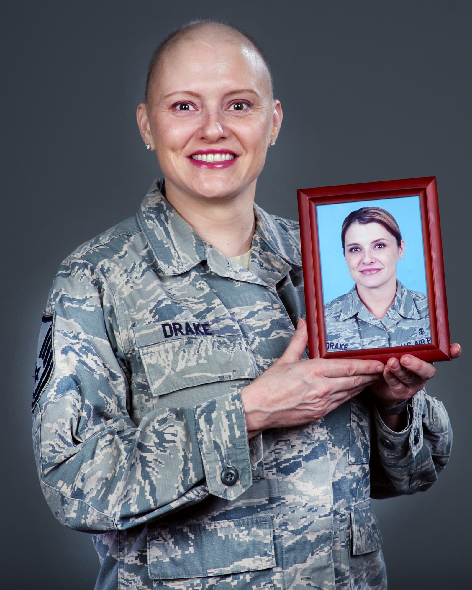 U.S. Air Force Master Sgt. Tracey Drake, 60th Medical Operations Squadron poses with a picture of herself prior to losing her hair from chemotherapy treatment, Travis Air Force Base, Calif., Dec. 15, 2016. Drake was diagnosed with metastatic breast cancer during her retirement physical in July 2016, 3 weeks before starting terminal leave. Drake faces more chemotherapy, surgery, radiation, targeted infusion, and reconstruction surgery. (U.S. Air Force photo/Louis Briscese)