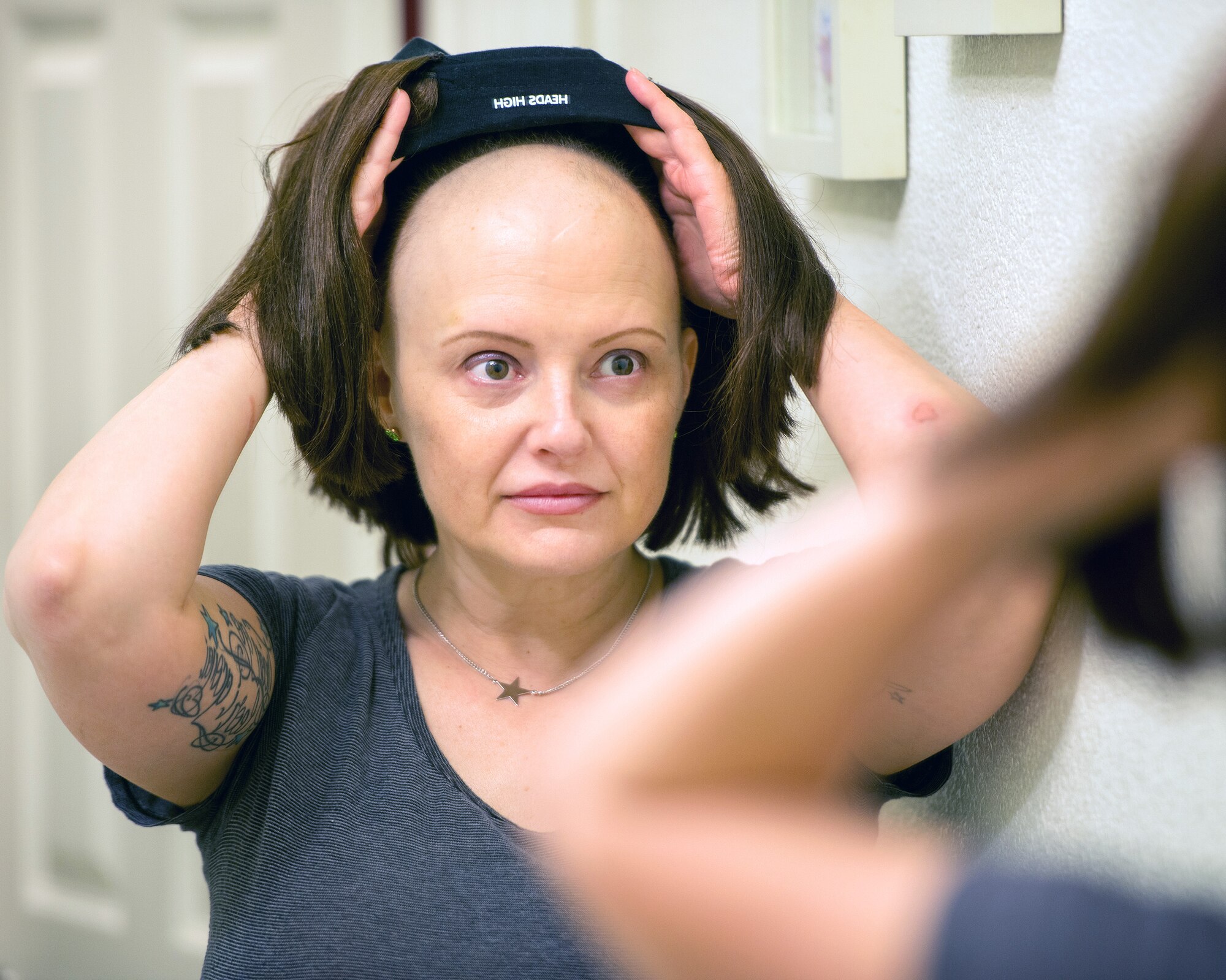 U.S. Air Force Master Sgt. Tracey Drake, 60th Medical Operations tries on a wig, Travis Air Force Base, Calif., Jan. 10, 2017. Drake was diagnosed with metastatic breast cancer during her retirement physical in July 2016, 3 weeks before starting terminal leave. Drake faces surgery, radiation, targeted infusion, and reconstruction surgery. (U.S. Air Force photo/Louis Briscese)