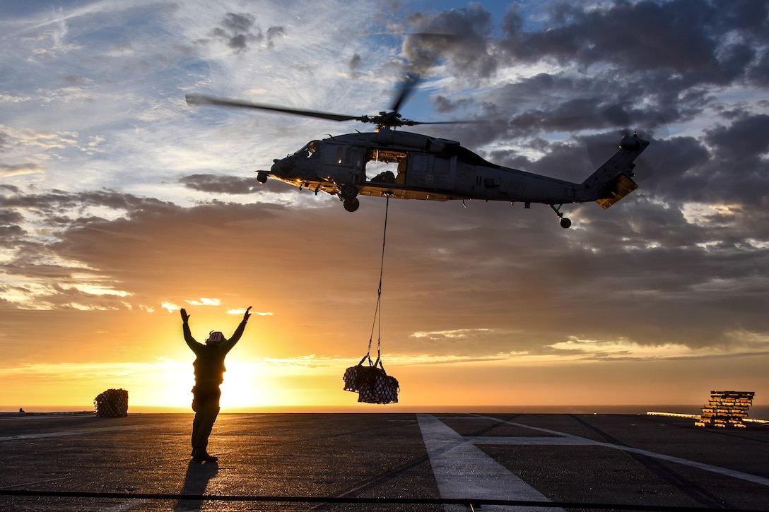 A sailor directs an MH-60S Seahawk helicopter to lower supplies onto the flight deck of the aircraft carrier USS Carl Vinson during a vertical replenishment with the fleet replenishment oiler USNS Yukon in the Pacific Ocean, Jan. 7, 2017. Navy photo by Petty Officer 2nd Class Sean M. Castellano