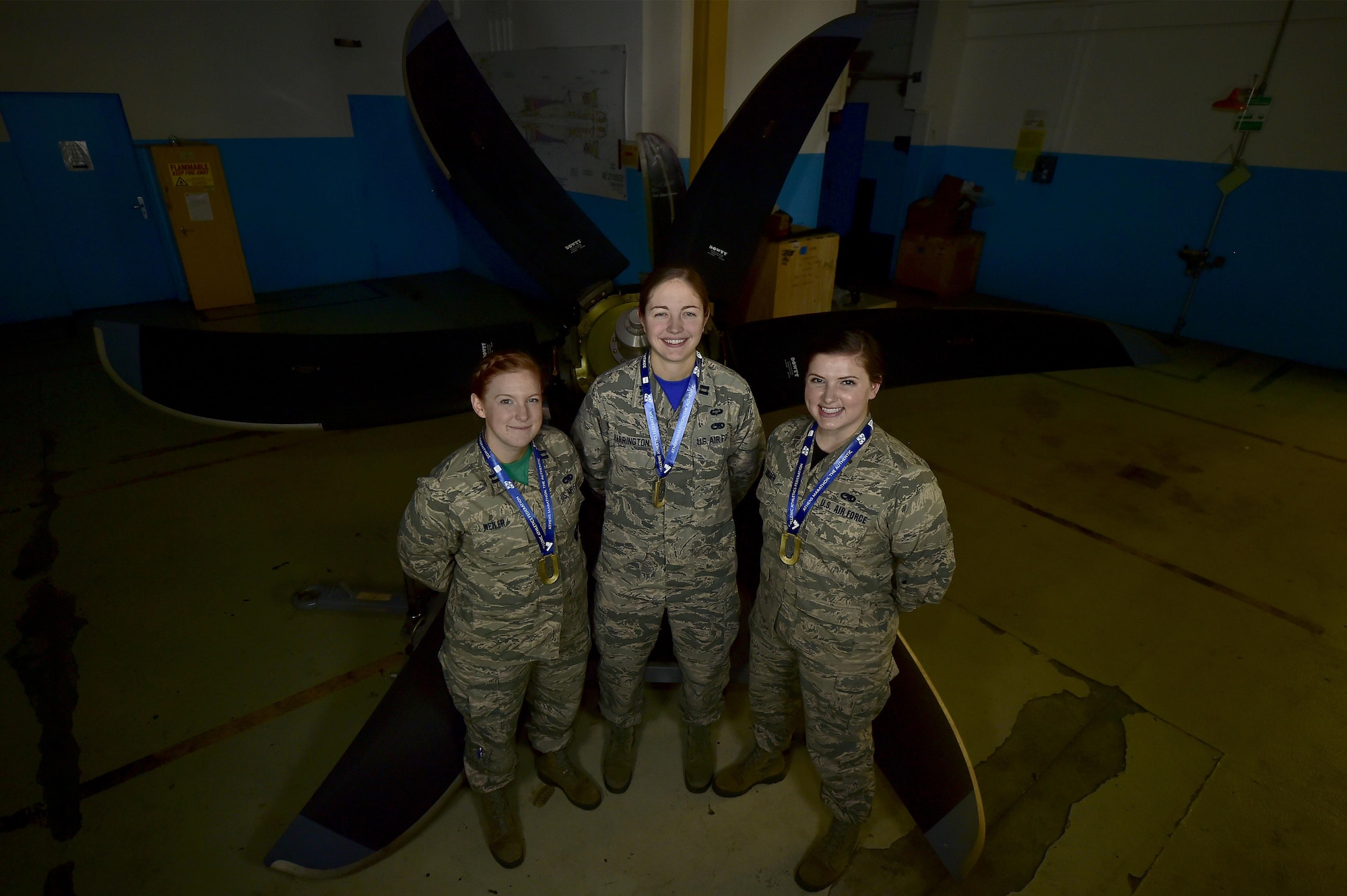 (From left) U.S. Air Force Capts. Rachel Weiler, Michelle Harrington, and 2nd Lt. Haley Janssen, all officers assigned to the 86th Maintenance Group, pose for a photo in front of a C-130J Super Hercules propeller at Ramstein Air Base, Germany, Jan. 6, 2017. The three company-grade officers recently completed their first marathon last November, in Athens, Greece, the location of the very first marathon ever ran. (U.S. Air Force photo by Senior Airman Jonathan Bass)