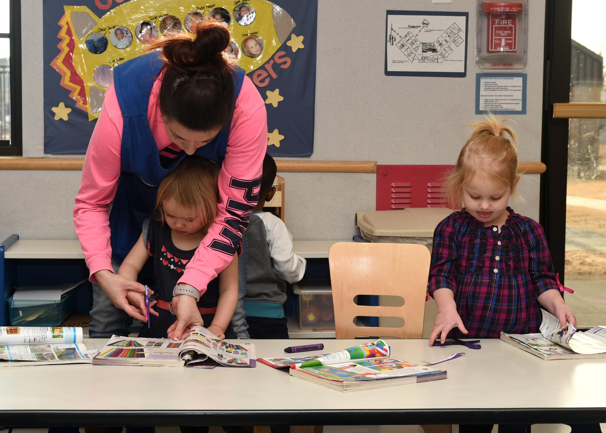 Michel Miklja, 97th Force support Squadron, Child Development Program Leader assists children with an arts and crafts project, January 4, 2017. The CDC provides a safe and healthy learning environment so that Department of Defense civilian and military personnel can focus on the mission knowing their children are well taken care of during the duty day.