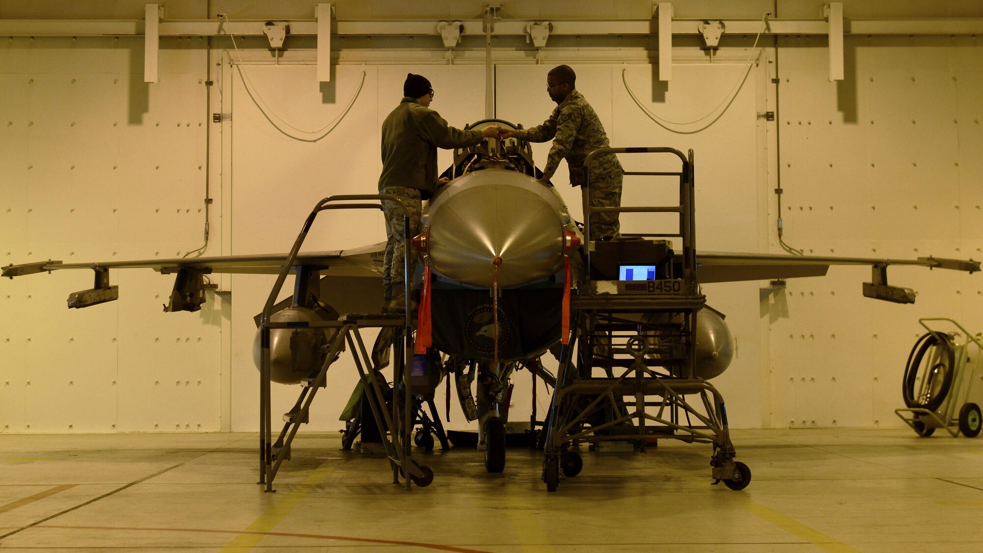 Senior Airman Glen Ratliff, 31st Maintenance Squadron Aircrew Egress Systems journeyman, and Staff Sgt. Chadwick Greer, 31st MXS Aircrew Egress Systems craftsman, install a detonating transfer assembly line in an F-16 Fighting Falcon at Aviano Air Base, Italy recently. The assembly line transfers an electrical signal to the ejection seat should a pilot need to pull the ejection lever in an emergency. (U.S. Air Force photo by Senior Airman Cary Smith)