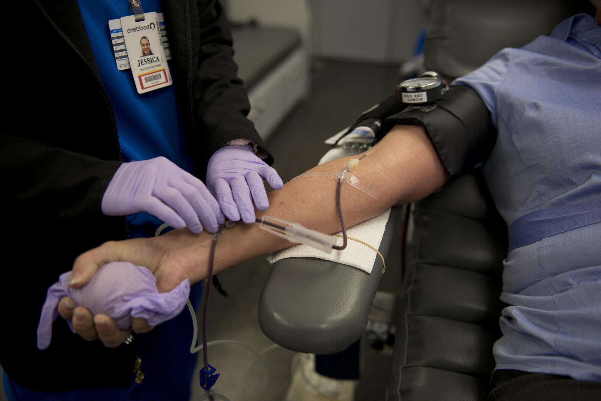 Jessica Barrett, OneBlood Drive bloodmobile team member, finishes setting up tubing on a donor’s arm during the blood donation process Jan. 10 at Eglin Air Force Base, Fla. All donors received wellness checkups, which included iron count; blood pressure; temperature check and cholesterol screenings. (U.S. Air Force photo/Kristin Stewart)