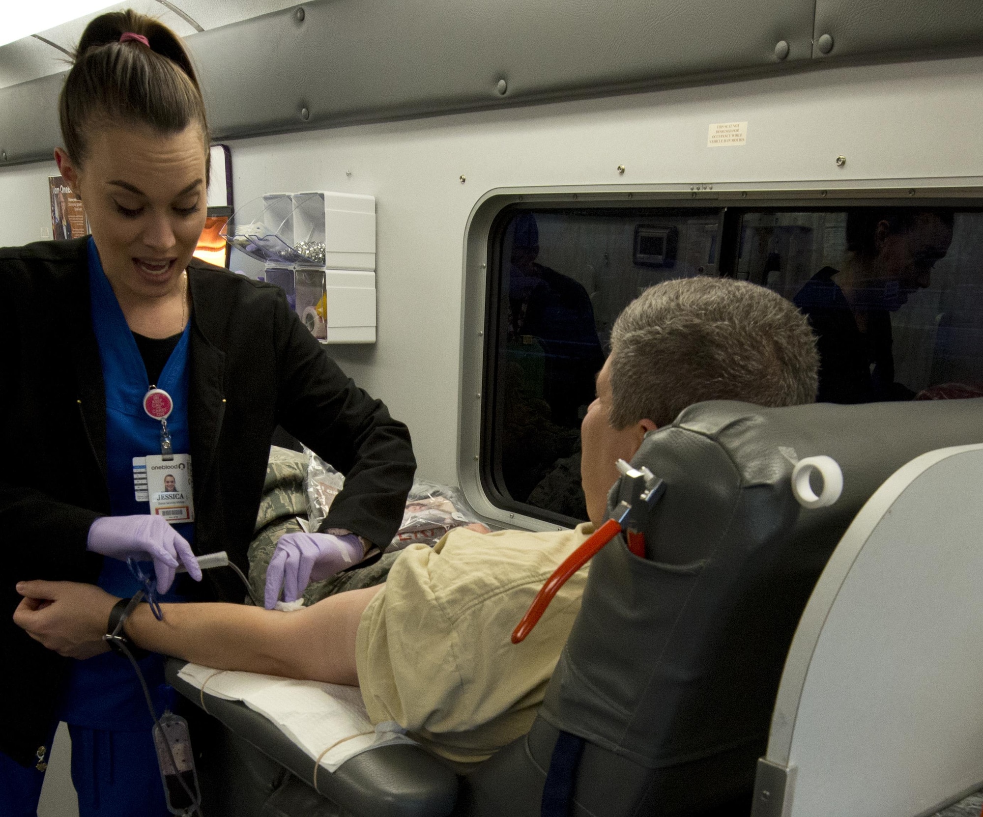 Jessica Barrett, OneBlood Drive bloodmobile team member, holds gauze in place while disconnecting the needle as Col. Michael Taylor, 96th Test Wing staff judge advocate, gives blood Jan. 10 at Eglin Air Force Base, Fla. All donors received wellness checkups, which included iron count; blood pressure; temperature check and cholesterol screenings. (U.S. Air Force photo/Kristin Stewart)