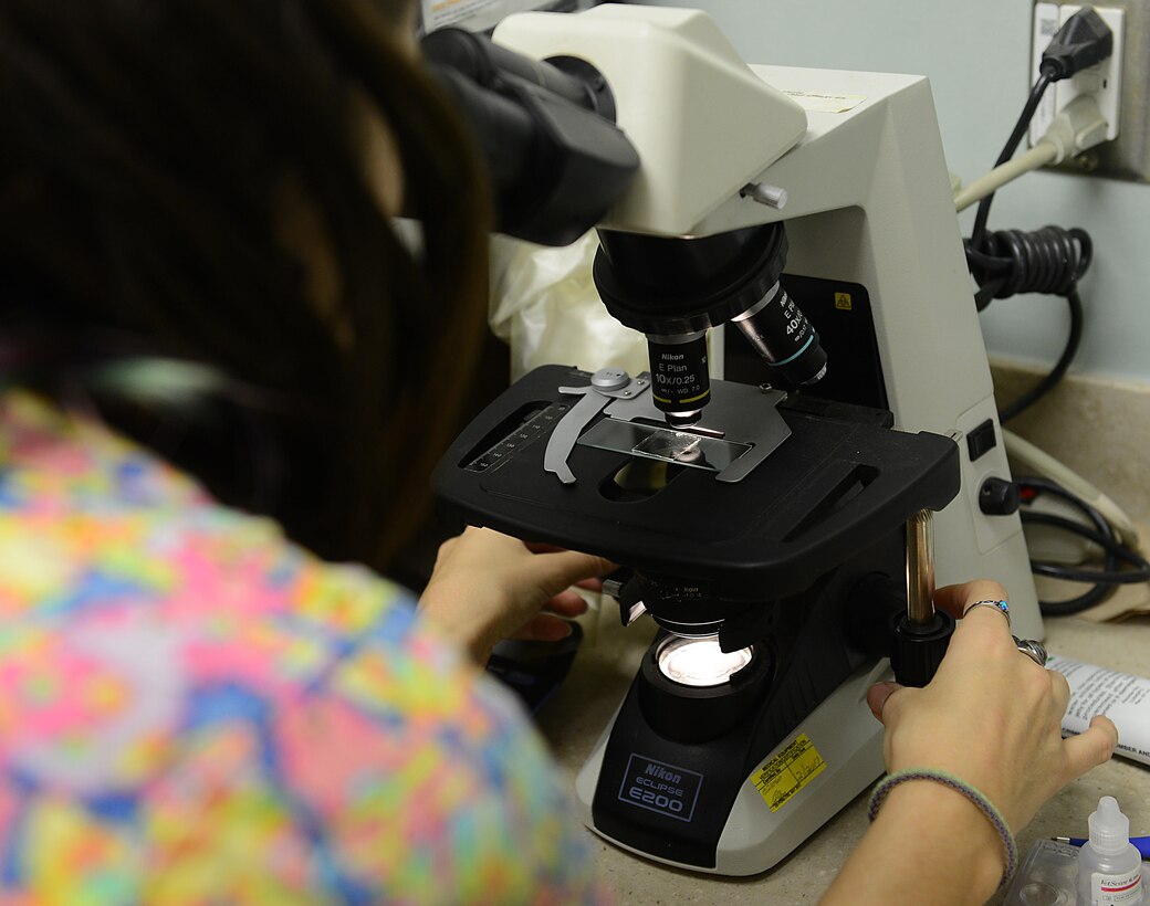 Jo Marie Edmister, Langley Veterinarian Clinic animal health care assistant, uses a microscope to inspect a K-9 lab sampleduring a routine check-up at Joint Base Langley-Eustis, Va., Jan. 5, 2017. Microscopic exams are used to detect and prevent of worms and certain bacteria that pets may be susceptible to based on their breed, age, and local environment. (U.S. Air Force photo by Staff Sgt. Teresa J. Cleveland)