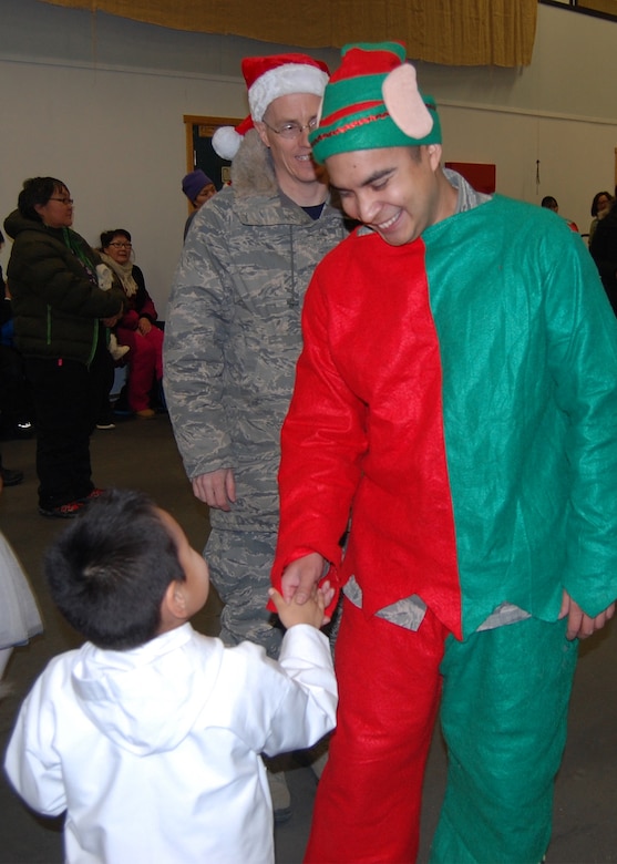 QAANAAQ, Greenland – Tech. Sgt. Oscar Nunez, 821st Air Base Group at Thule Air Base, Greenland, shakes the hand of a child during Operation Julemond in the local community of Qaaanaaq, Dec. 22, 2016. Village families gather every year to celebrate the international relationship with songs around the Christmas tree, hugs, laughter and gifts. (U.S. Air Force photo by Tech. Sgt. Shawn Joseph)