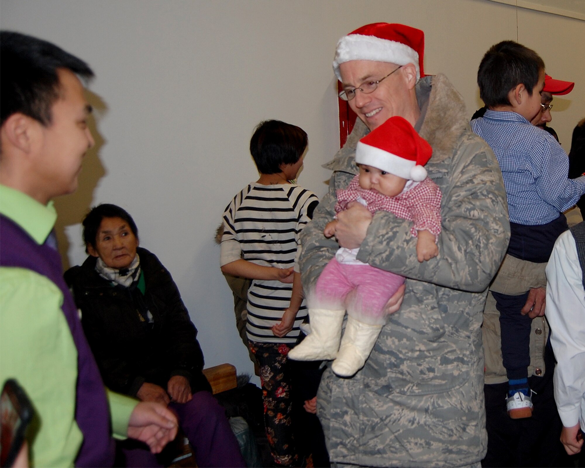 QAANAAQ, Greenland – Col. Chris Eagan, 821st Air Base Group commander at Thule Air Base, Greenland, holds the child of a community member during Operation Julemond held in the local community Dec. 22, 2016. Since 1959, the members of Thule have nurtured a special relationship with their nearest neighbors about 159 kilometers up the coast from the base. (U.S. Air Force photo by Tech. Sgt. Shawn Joseph)