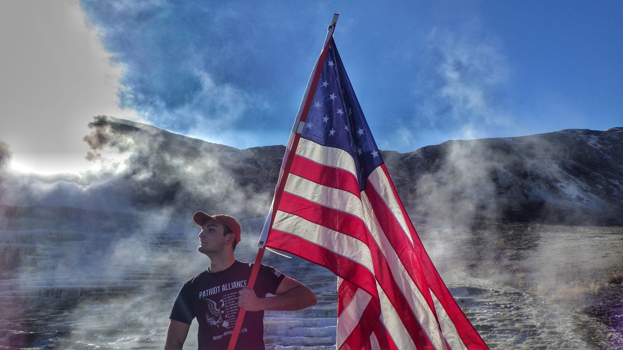 Staff Sgt. Jonathan Balko, an electrical and environmental craftsman assigned to the 28th Aircraft Maintenance Squadron, proudly holds his flag at Mammoth Hot Springs in Yellowstone National Park, Wyoming. From a young age, Balko knew he wanted to have a career related to military aviation. (Courtesy photo)