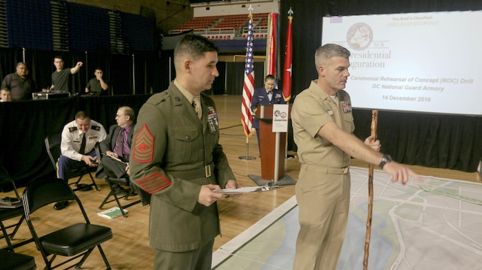 Master Sgt. Alex Barros (left), a project officer in Marine Corps Systems Command’s Expeditionary Power Systems, discusses plans on a 60-by-40-foot map during the ceremonial rehearsal of concept drill at the National Guard Armory in Washington, D.C., Dec. 14. Barros was selected in October to serve on the Joint Task Force-National Capital Region, which was assembled to support the 58th Presidential Inauguration. On Jan. 20, more than 5,000 service members will participate in the inauguration ceremonies and other events. (U.S. Army photo by Spc. L'Erin Wynn)