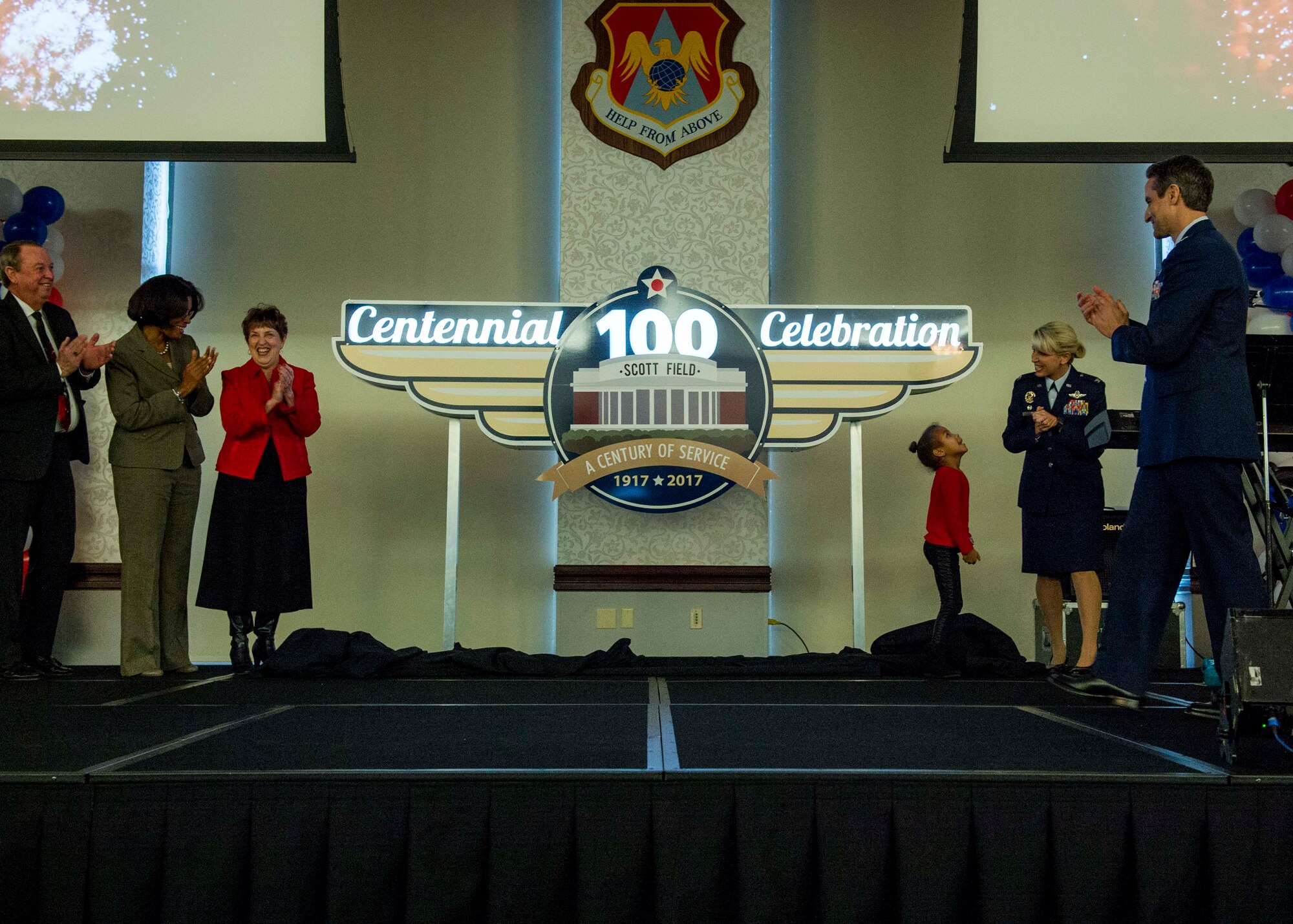 Mayor Mark Eckert, Charles Vernier, retired Chief Master Sgt. Pamela Dorsey, Margaret Foerste, 5-year-old Devyn Baggett, and Col. Laura Lenderman, 375th Air Mobility Wing commander, unveil the Centennial signage commemorating the 100th anniversary of Scott Air Force Base. (U.S. Air Force photo by Staff Sgt. Jodi Martinez)