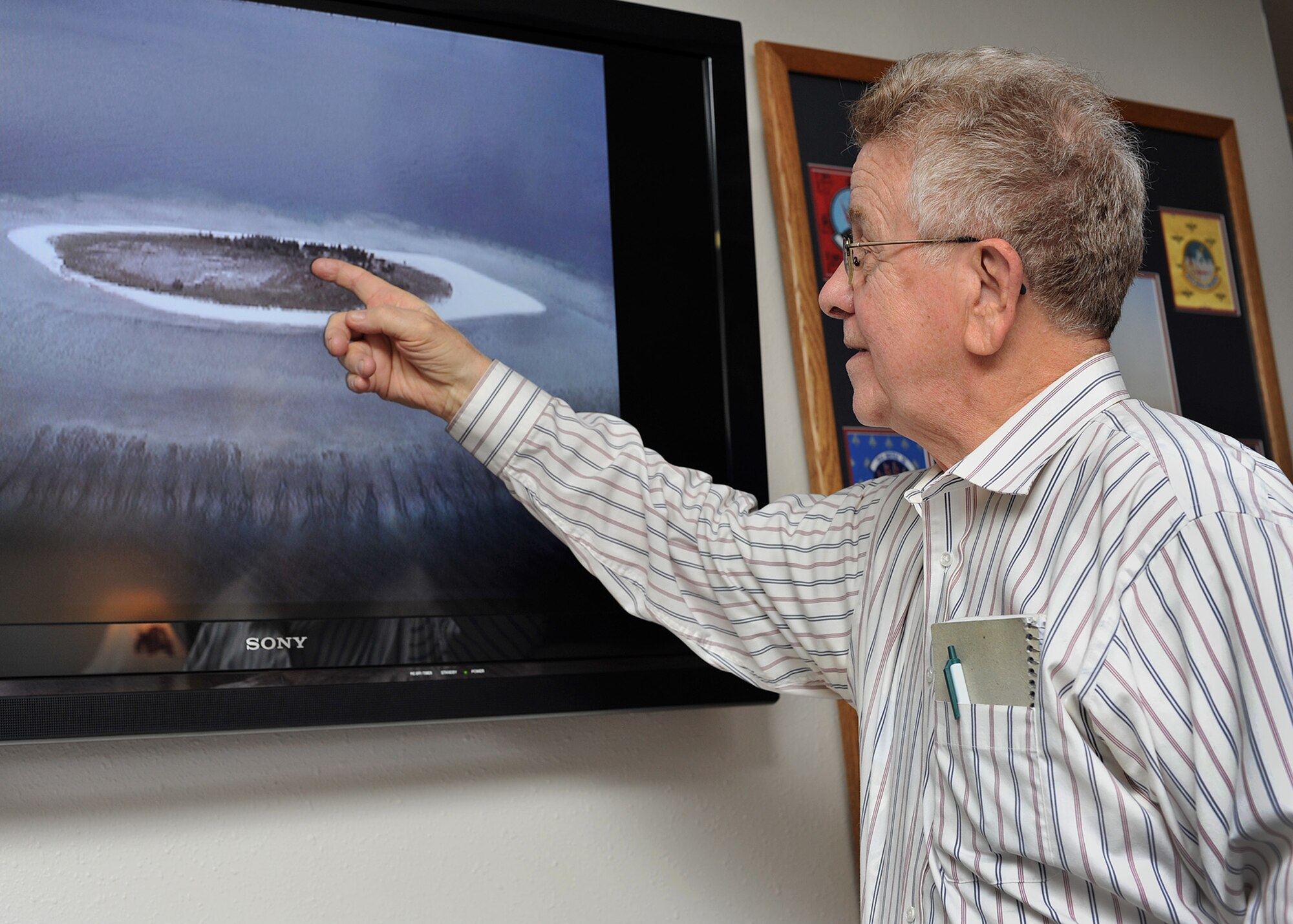 Bob Cunningham points to the camp on ‘North Danger Island’ where he lived and worked as a radar operator for six months in 1956 during an Air Force project mapping the Earth. His team was resupplied with food, water, medicine, parts and mail every four to six weeks at the remote location in the South China Sea. Cunningham visited the Malmstrom Air Force Base museum Dec. 22, 2016, and showed photographs he took during his tour of duty on the island. (U.S. Air Force photo/John Turner)