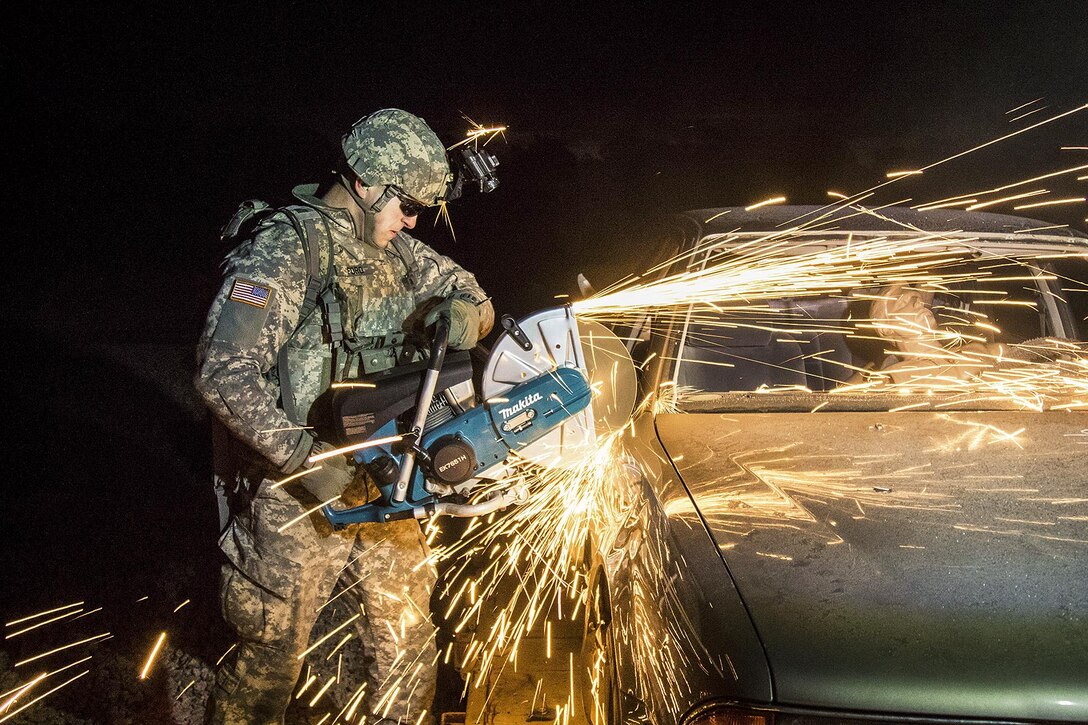 A soldier simultaneously uses a buzz saw to slice the door of a simulated down aircraft during training at Fort Bragg, N.C., Jan 10, 2017. The soldier is assigned to the 122nd Aviation Support Battalion, 82nd Combat Aviation Brigade Downed Aircraft Recovery Team. Army photo by Sgt. Steven Galimore