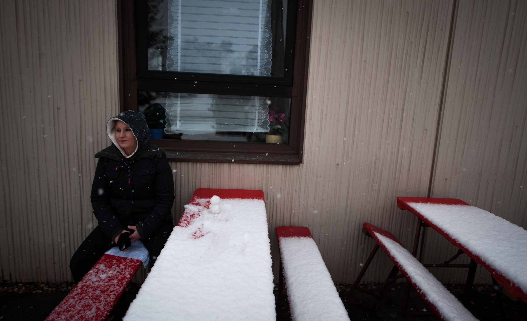 A woman sits outside a restaurant during snow fall at Ramstein Air Base, Germany, Jan. 10, 2017. In the last week, temperatures reached a low of seven degrees Fahrenheit, the coldest period of inclimate weather since 2015. (U.S. Air Force photo by Airman 1st Class Lane T. Plummer)