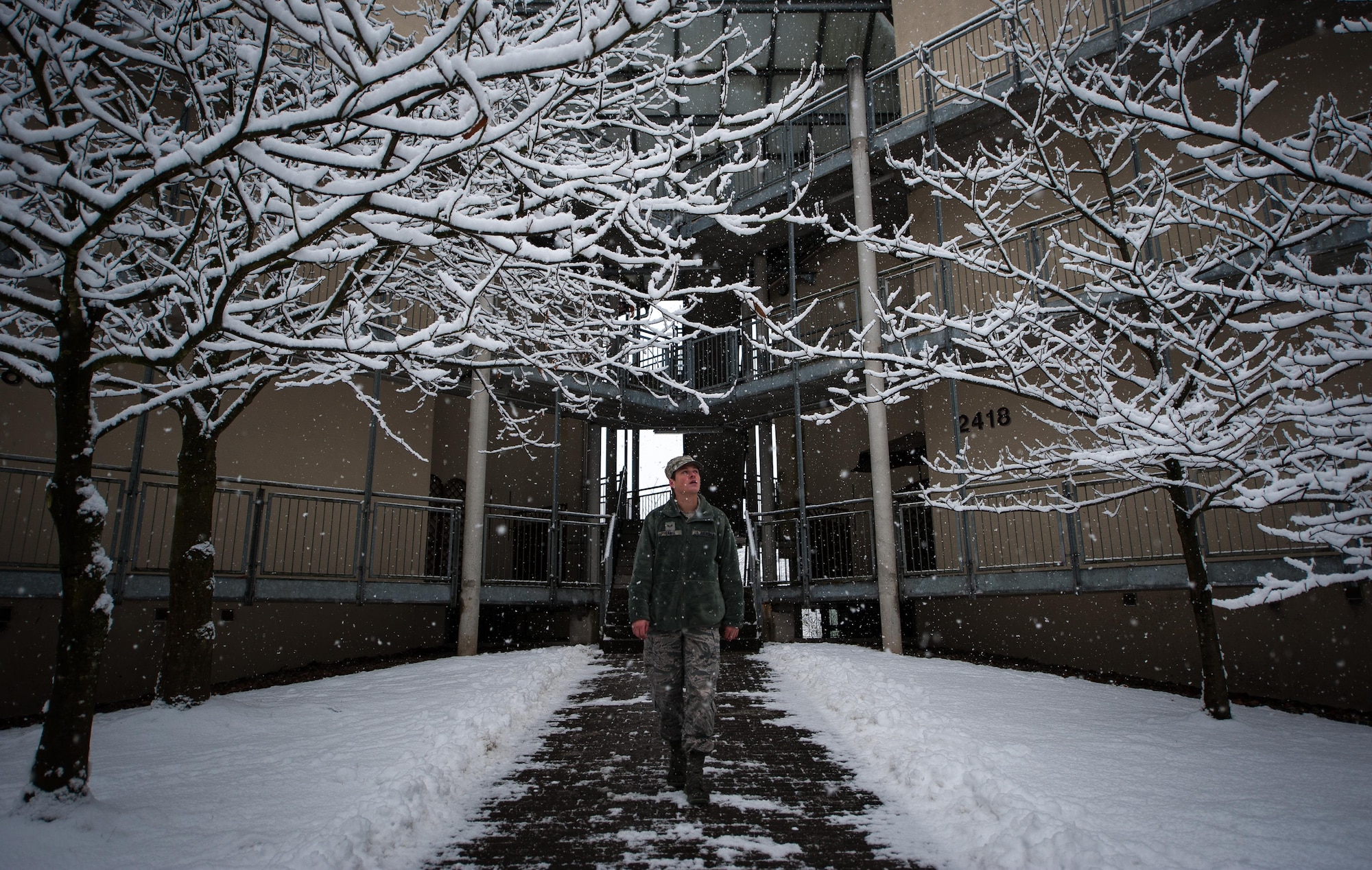 Senior Airman Collin Sams, 786th Force Support Squadron installation personnel readiness technician, walks outside his dormitory at Ramstein Air Base, Germany, Jan. 10, 2017. Sams was part of a bay orderly team in charge of maintaining cleanliness around dormitories across Ramstein, and cleared walkways and parking lots of snow throughout the day as precipitation fell. . (U.S. Air Force photo by Airman 1st Class Lane T. Plummer)