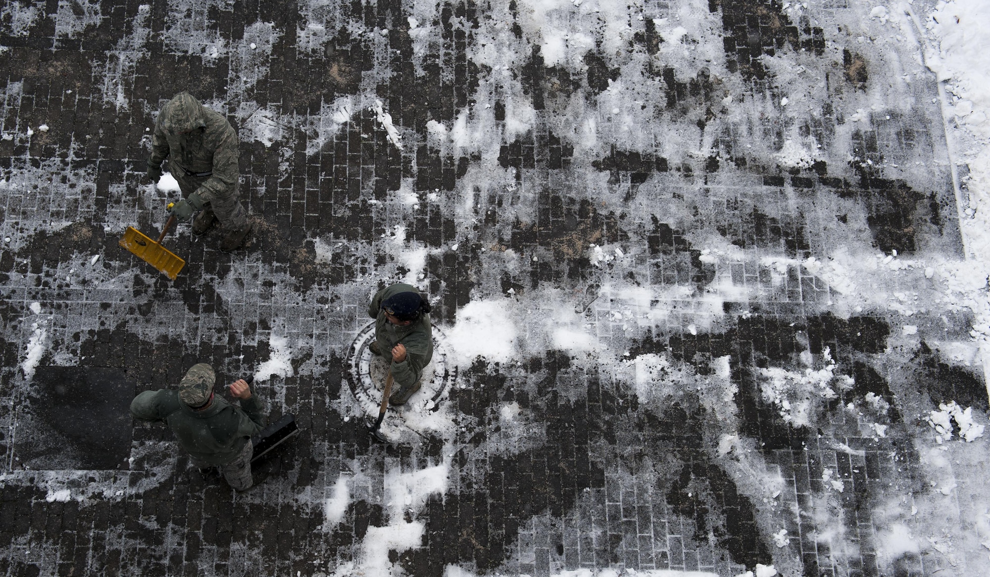 Airmen shovel away snow from the pavement surrounding their dormitory at Ramstien Air Base, Germany, Jan. 10, 2017. The Airmen were part of a bay orderly team in charge of maintaining cleanliness around dormitories across Ramstein, and cleared walkways and parking lots of the record 3 1/2 inches of snow that fell throughout the day. (U.S. Air Force photo by Airman 1st Class Lane T. Plummer)