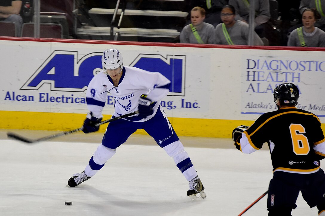 Air Force Senior Airman Nate Skoog, left, takes a slap shot against an Army defender in the first period during the 4th Annual Army vs. Air Force Hockey game at the Sullivan Arena in Anchorage, Alaska, Jan. 7, 2017. Army photo by John Pennell