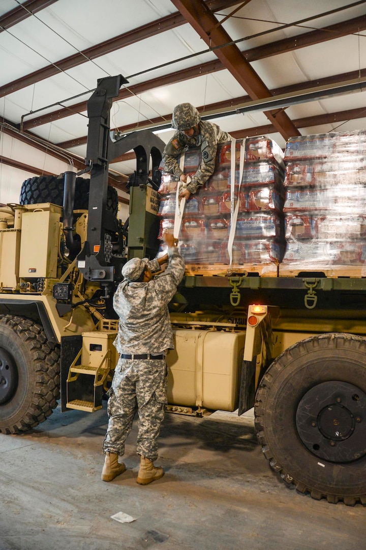 Members of the Louisiana National Guard's 1086th Transportation Company, and Pfc. Mason Madrigal, a Bunkie, Louisiana native, secure pallets of bottled water on a palletized load system vehicle to be delivered to the town of St. Joseph, Jan. 5, 2017. The LANG received the mission to deliver water after Gov. John Bel Edwards declared a public health emergency due to elevated levels of lead and copper in the water.