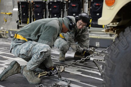 Airmen 1st Class Marcus Downey and Kewei Yu, 43rd Air Mobility Squadron porters, secure a Humvee to the deck of a C-17 Globemaster III during a Deployment Readiness Exercise on Pope Army Airfield Jan. 9, 2017. As part of the exercise, the 43rd AMS brought cargo to the flightline, loaded and then unloaded the aircraft to test the 43rd Air Mobility Operations Group on how they prepare and load cargo for deployment. (U.S. Air Force photo by Master Sgt. Thomas J. Doscher/released)