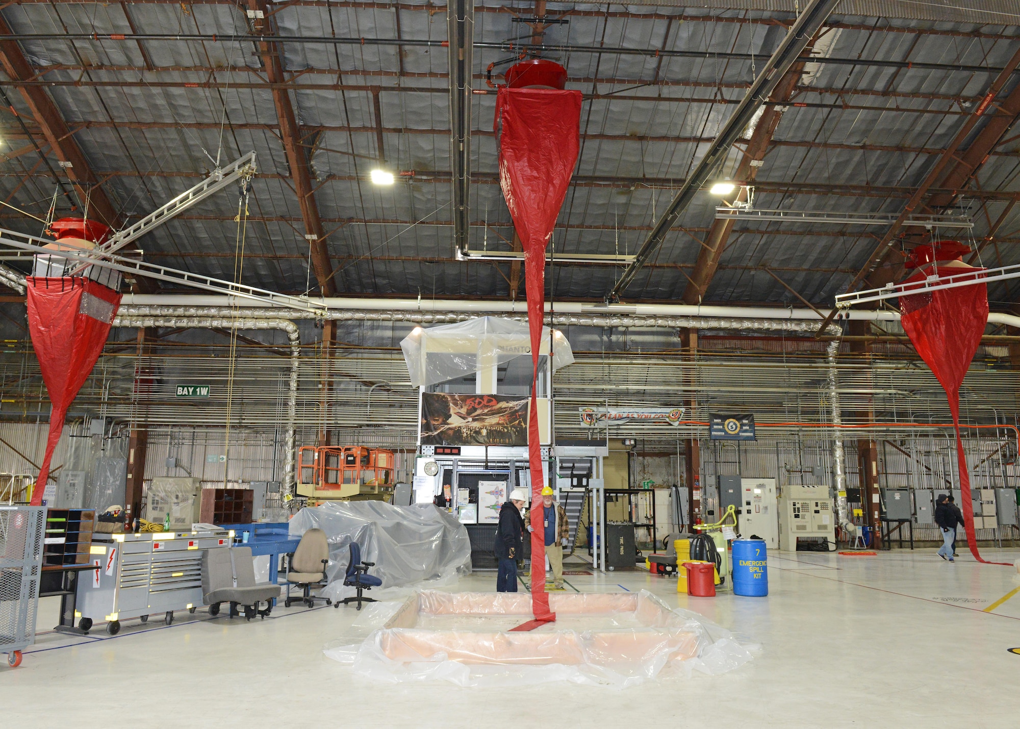 Red plastic funnels were affixed to ten fire suppression foam dispensers in Hangar 1820’s west side to conduct a test of the fire suppression system Jan. 8. Base civil engineers and the Edwards Air Force Base Fire Department used water to test the dispensers, which funneled down to a makeshift containment pool. Using this new funnel test system saved the base $79,750 according to the testers. (U.S. Air Force photo by Kenji Thuloweit)