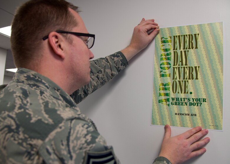 Senior Master Sgt. Benjamin A. Schaub, community support coordinator, displays a Green Dot poster in the Community Support Center Jan. 12. The office of the specialist for the primary prevention of violence here will collaborate with local commanders and directors Jan. 18 to kick off the Green Dot Chip Challenge. The challenge encourages and inspires employees to do a proactive Green Dot action by Jan. 25. (U.S. Air Force photo by Mark Herlihy)

