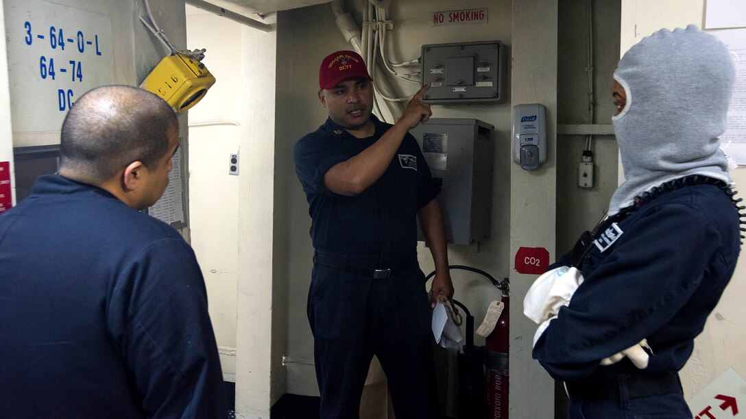 Navy Petty Officer 1st Class Rene Lopez, center, explains the responsibilities of the Damage Control Training Team to Navy Chief Petty Officer Mike Ramil, left, and Petty Officer 2nd Class Jemmerria McBride during a general quarters drill aboard the aircraft carrier USS Carl Vinson in the Pacific Ocean, Jan. 9, 2017. Lopez is a damage controlman, Ramil is an engineman and McBride is a quartermaster. Navy photo by Petty Officer 2nd Class D’Andre L. Roden
