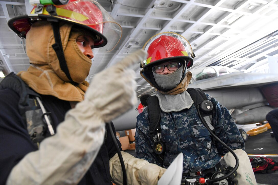 Navy Seaman Daylan Anderson, left, briefs Seaman Brooke Enslin about safety procedures during a general quarters drill in the hangar bay aboard the aircraft carrier USS Carl Vinson in the Pacific Ocean, Jan. 9, 2017. Anderson and Enslin are Electrician’s Mate Firemen. Navy photo by Chief Amanda Dunford 