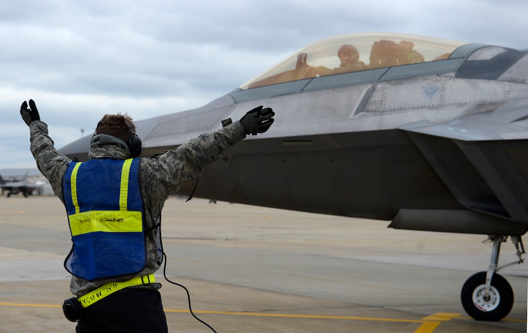 U.S. Air Force Senior Airman Jakob Miner, 1st Aircraft Maintenance Squadron crew chief, signals an F-22 Raptor to stop at a hydrogen pit for a hot pit refuel at Joint Base Langley-Eustis, Va., Jan. 6, 2017. Hydrogen pits are connected to underground pipes that allow fuel to flow from nearby storage tanks. (U.S. Air Force photo by Airman 1st Class Kaylee Dubois)