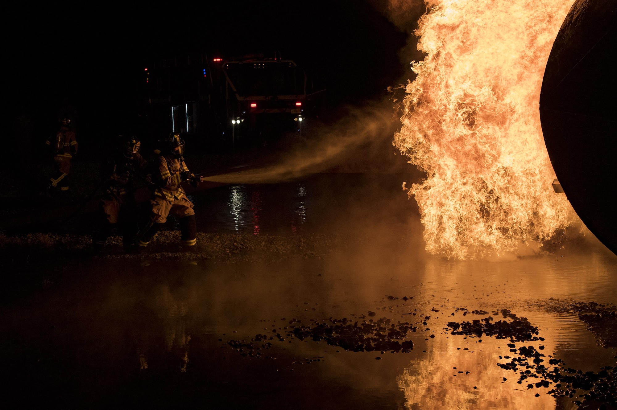 Firefighters from the 23d Civil Engineer Squadron team up to extinguish flames during nighttime, live-fire training, Jan. 10, 2017, at Moody Air Force Base, Ga. The prop aircraft fires were propane-controlled by the fire department’s assistant chief of training, Charlie Johnson. (U.S. Air Force photo by Airman 1st Class Daniel Snider)