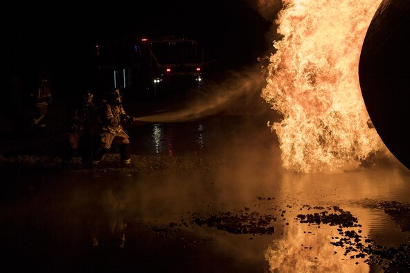 Firefighters from the 23rd Civil Engineer Squadron team up to extinguish flames during nighttime, live-fire training, Jan. 10, 2017, at Moody Air Force Base, Ga. The prop aircraft fires were propane-controlled by the fire department’s assistant chief of training, Charlie Johnson. (U.S. Air Force photo by Airman 1st Class Daniel Snider)