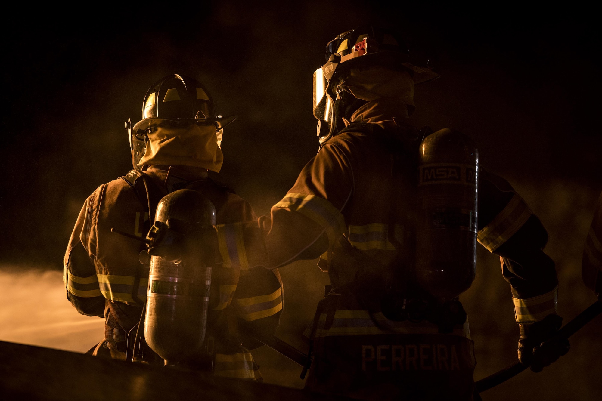 Matthew Perreira, right, 23d Civil Engineer Squadron firefighter, backs up a fellow firefighter during nighttime, live-fire training, Jan. 10, 2017, at Moody Air Force Base, Ga. This training is an annual requirement for Moody firefighters and is just one of the ways they stay ready to protect people, property and the environment from fires and disasters. (U.S. Air Force photo by Staff Sgt. Ryan Callaghan)
