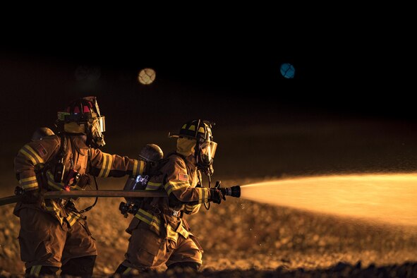 Firefighters from the 23rd Civil Engineer Squadron advance towards a fire during nighttime, live-fire training, Jan. 10, 2017, at Moody Air Force Base, Ga. This training is an annual requirement for Moody firefighters and is just one of the ways they stay ready to protect people, property and the environment from fires and disasters. (U.S. Air Force photo by Staff Sgt. Ryan Callaghan)
