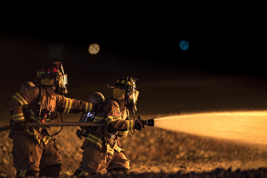 Firefighters from the 23d Civil Engineer Squadron advance towards a fire during nighttime, live-fire training, Jan. 10, 2017, at Moody Air Force Base, Ga. This training is an annual requirement for Moody firefighters and is just one of the ways they stay ready to protect people, property and the environment from fires and disasters. (U.S. Air Force photo by Staff Sgt. Ryan Callaghan)
