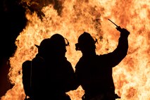 Firefighters from the 23d Civil Engineer Squadron signal for a radio check prior to advancing on a fire during nighttime, live-fire training, Jan. 10, 2017, at Moody Air Force Base, Ga. This training is an annual requirement for Moody firefighters and is just one of the ways they stay ready to protect people, property and the environment from fires and disasters. (U.S. Air Force photo by Staff Sgt. Ryan Callaghan)
