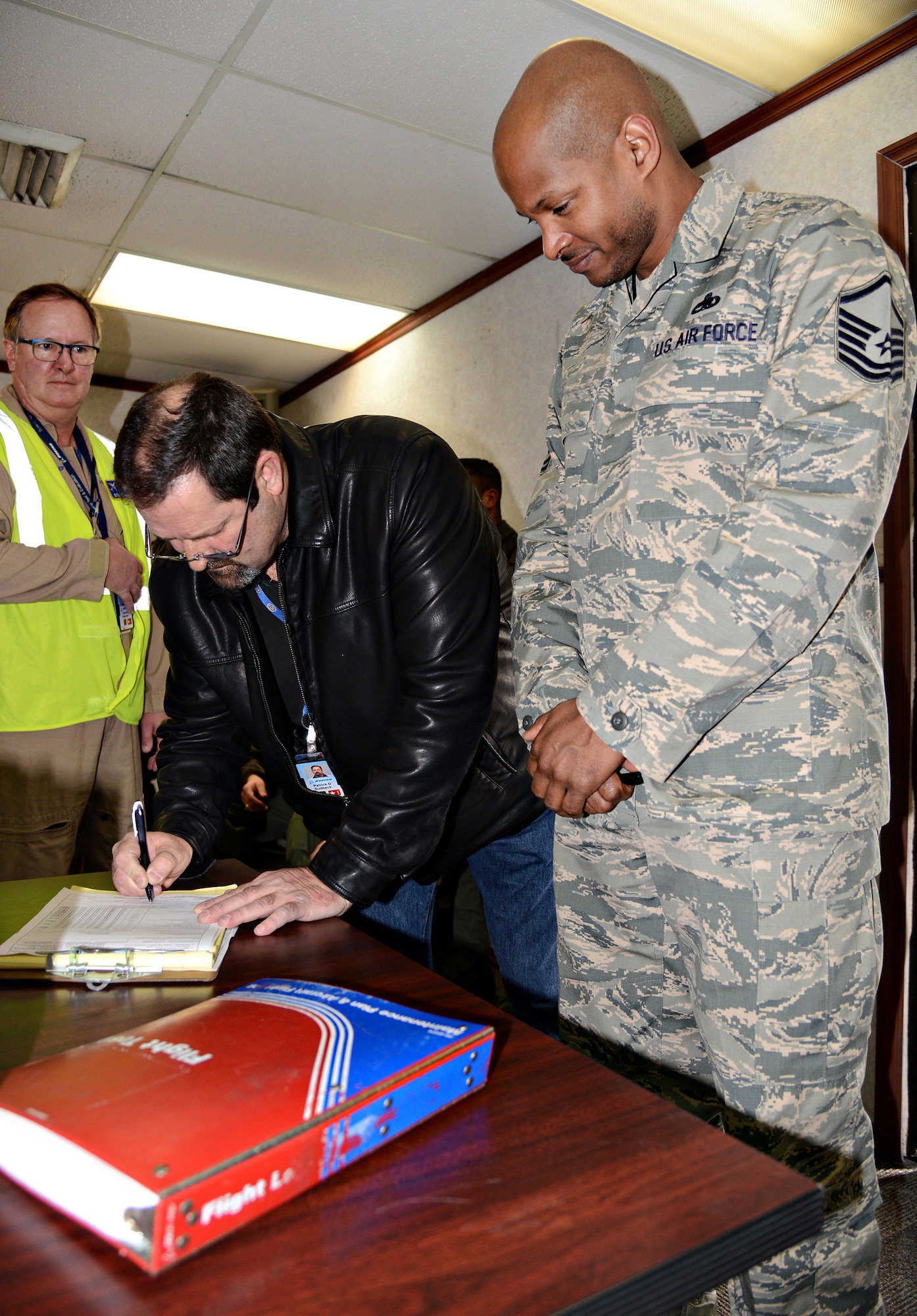 A representative from Boeing signs the paperwork transferring the first of 24 E-3 Sentry aircraft to undergo DRAGON cockpit modernization, back to the 552nd Air Control Wing.  Accepting for the 552nd ACW is Master Sgt. Maliek, 552nd Maintenance Group depot liaison. (Air Force photo by Kelly White)