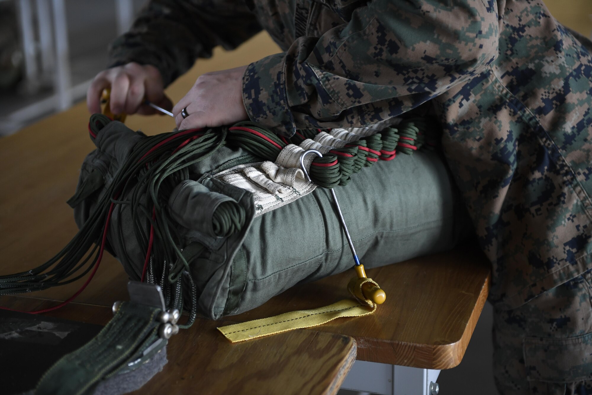 A Marine with the 3rd Reconnaissance Battalion, 3rd Marine Division, III Marine Expeditionary Force, stows suspension lines preparing a parachute on Jan. 11, 2017, at Yokota Air Base, Japan. The Marine unit spent the week working on their parachute qualifications practicing static line and high-altitude, low-opening jumps. (U.S. Air Force photo by Airman 1st Class Donald Hudson)