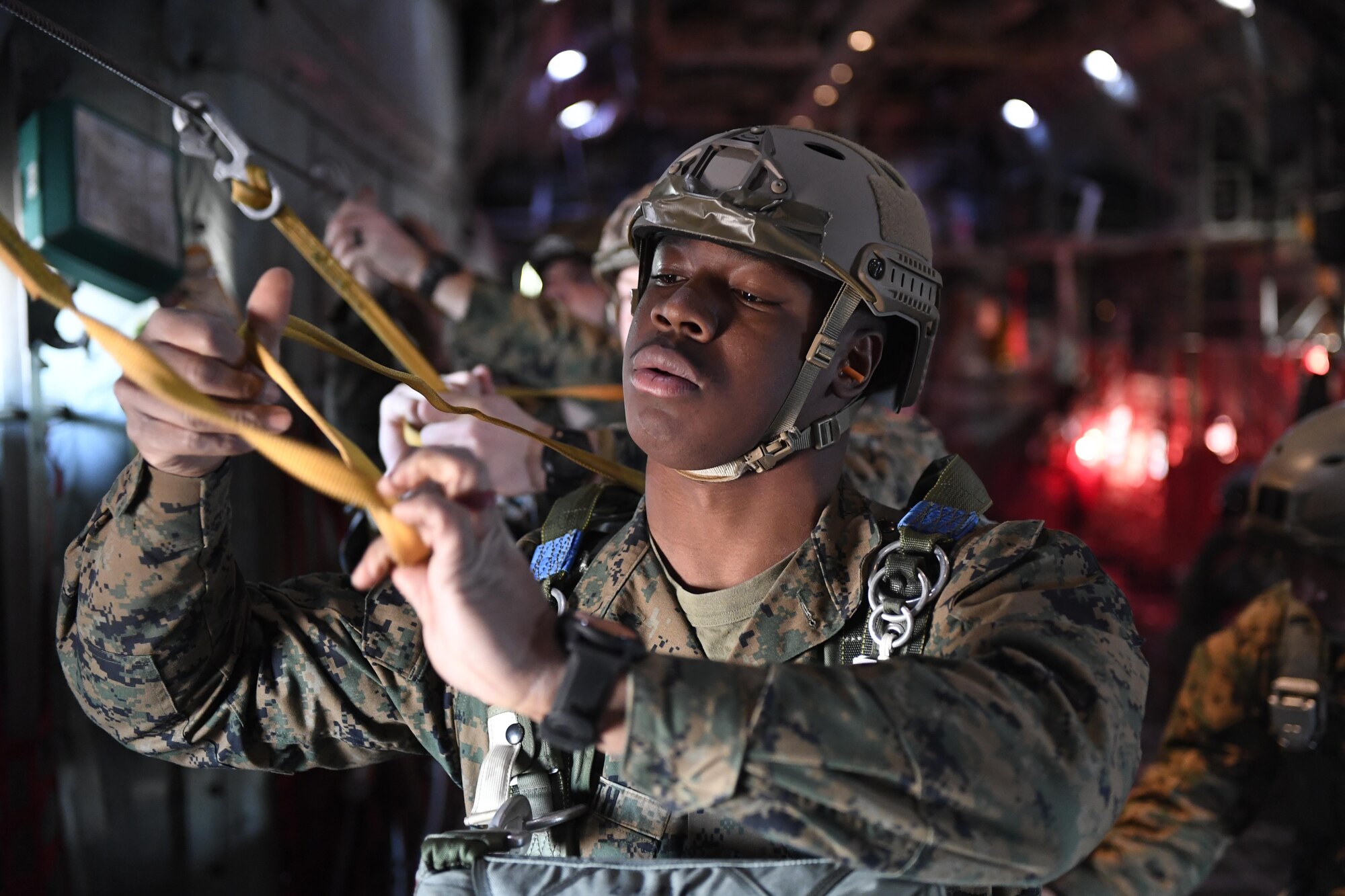 A Marine with the 3rd Reconnaissance Battalion, 3rd Marine Division, III Marine Expeditionary Force, hooks up and prepares to perform a static line parachute jump from a C-130 Hercules on Jan. 11, 2017, at Yokota Air Base, Japan. The training allowed Marines to practice jumping while also allowing Yokota aircrews to practice flight tactics and timed-package drops. (U.S. Air Force photo by Airman 1st Class Donald Hudson)