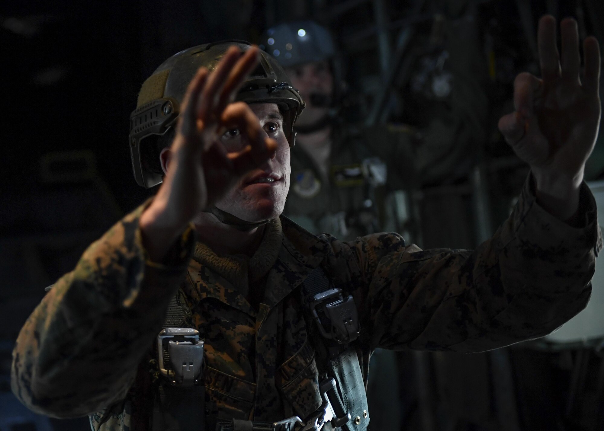 A Marine with the 3rd Reconnaissance Battalion, 3rd Marine Division, III Marine Expeditionary Force, jump master instructs fellow Marines using hand signals while flying in a C-130 Hercules before a static line parachute drop on Jan. 11, 2017, at Yokota Air Base, Japan. The training ensures that jumpers and flight crew are ready to respond to real world events throughout the Indo-Asia Pacific region. (U.S. Air Force photo by Airman 1st Class Donald Hudson)