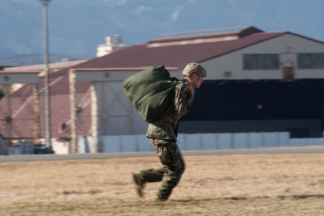 A U.S. Marine from the 3rd Reconnaissance Battalion, 3rd Marine Division, III Marine Expeditionary Force runs with his parachute after landing at Yokota Air Base, Japan, Jan. 10, 2017, during Jump Week. The training not only allowed the Marines to practice jumping, but it also allowed the Yokota aircrews to practice flight tactics and timed-package drops. (U.S. Air Force photo by Yasuo Osakabe/Released)  