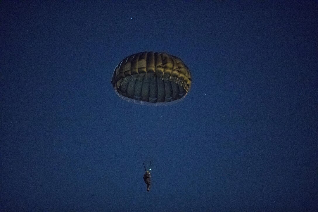 A U.S. Marine from the 3rd Reconnaissance Battalion, 3rd Marine Division, III Marine Expeditionary Force descends to the drop zone after exiting from an Air Force C-130 Hercules, assigned to the 36th Airlift Squadron at Yokota Air Base, Japan, Jan. 11, 2017, during Jump Week. The training not only allowed the Marines to practice jumping, but it also allowed the Yokota aircrews to practice flight tactics and timed-package drops. (U.S. Air Force photo by Yasuo Osakabe/Released)  