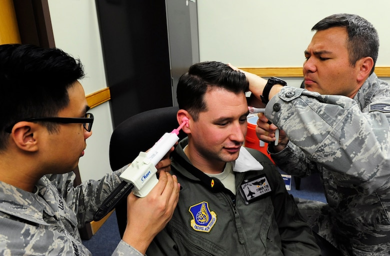 Staff Sgt. Marion Franco, 8th Medical Operations Squadron aerospace and operational Physiology Technician, and Staff Sgt.  Edward Todd, 8th Medical Operations Squadron dental laboratory technician, insert silicone based mixture into the ear of Capt. Connor Flynt, 35th Fighter Squadron F-16 pilot, to make an inner-ear mold for the Attenuating Custom Communications Earpiece System at Kunsan Air Base, Republic of Korea, Jan. 9, 2017. The ACCES device will significantly reduce surrounding ambient noise that pilots hear in the cockpit and increase the efficiency of radio communications. (U.S. Air Force photo by Staff Sgt. Chelsea Browning/Released)