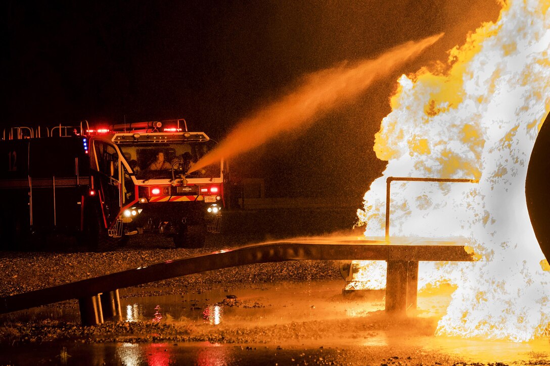 A vehicle drenches a prop aircraft during night firefighting training at Moody Air Force Base, Ga., Jan. 10, 2017. Air Force photo by Airman 1st Class Daniel Snider