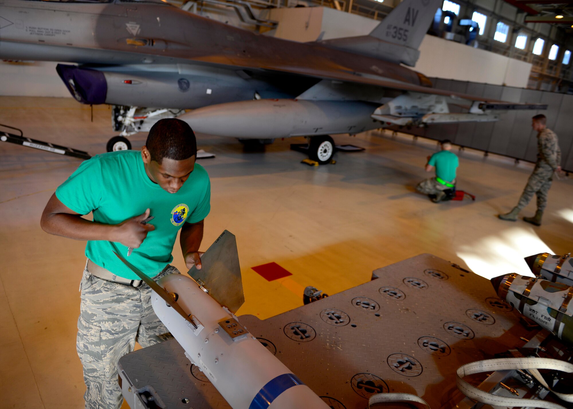 Senior Airman Travis Campbell, 31st Aircraft Maintenance Squadron weapons load crew member, prepares to load an inert munition on an F-16 Fighting Falcon during the annual load competition at Aviano Air Base, Italy on January 6, 2017. The three 3-person teams were judged on their job knowledge, dress and appearance, and munitions load performance. (U.S. Air Force photo by Senior Airman Areca T. Bell)