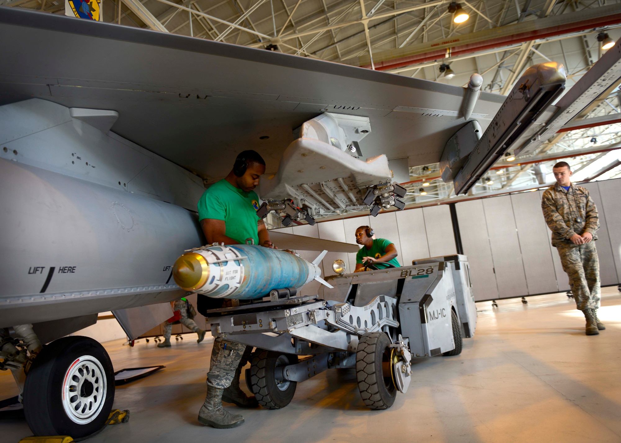 Staff Sgt. Ian Postler, right, load competition judge, observes Staff Sgt. Devon Sheffey, left, 31st Aircraft Maintenance Squadron weapons load crew chief and Senior Airman Travis Campbell, center, 31st AMXS weapons load crew member, load an inert munition on to an F-16 Fighting Falcon during the annual load competition at Aviano Air Base, Italy on January 6, 2017. Three 3-person teams competed for the title of the 31st Fighter Wing’s best weapons load crew of the year. The winning team will be announced during the Maintenance Professional of the Year Banquet.  (U.S. Air Force photo by Senior Airman Areca T. Bell)