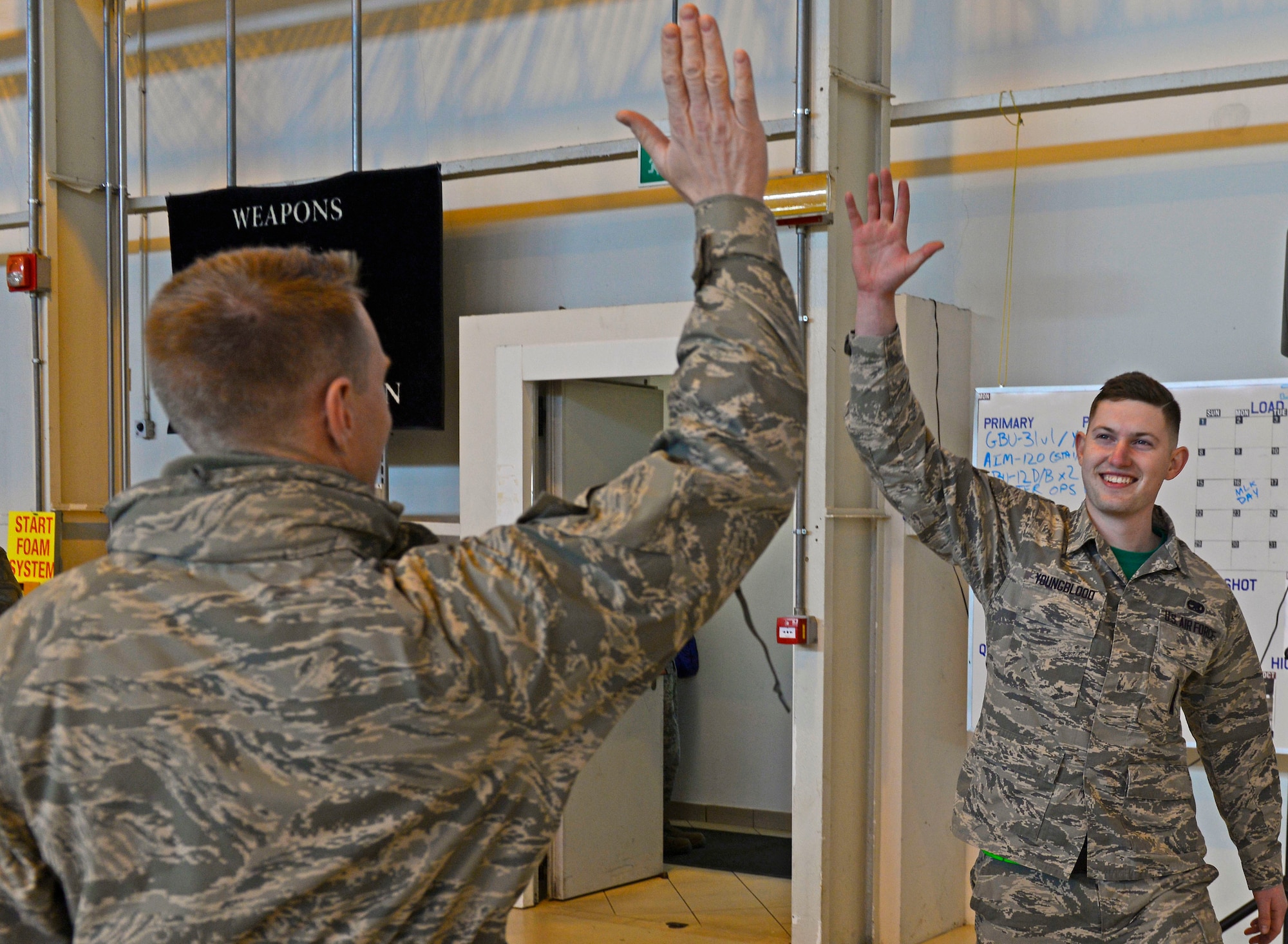 Airman 1st Class Matthew Youngblood, 31st Aircraft Maintenance Squadron weapons load crew member, high-fives Brig. Gen. Lance Landrum, 31st Fighter Wing commander, during the annual load competition at Aviano Air Base, Italy on Jan. 6, 2016. The three, 3-person teams were judged on their job knowledge, dress and appearance, and munitions load performance. (U.S. Air Force photo by Senior Airman Cary Smith)