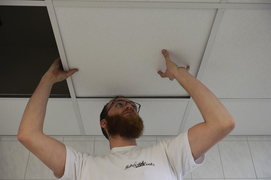 Lukas Denser, a carpenter, installs ceiling tiles in a restroom at the Northside Fitness Center on Ramstein Air Base, Germany, Jan. 13, 2017. The facility is undergoing renovations for its restrooms, locker rooms, and weight room. (U.S. Air Force photo by Airman 1st Class Joshua Magbanua)