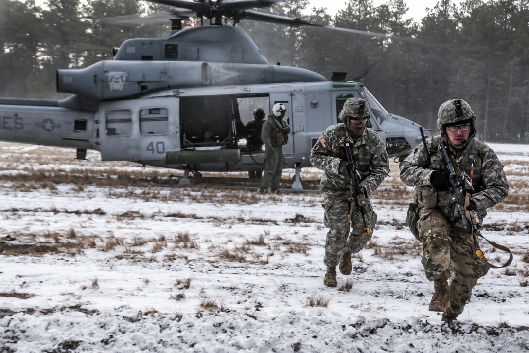 New Jersey Army National Guardsmen run toward the wood line after an air insertion by Marine Corps Reserve UH-1Y Huey helicopters during a joint-training exercise at Joint Base McGuire-Dix-Lakehurst, N.J., Jan. 10, 2017. Air National Guard photo by Tech. Sgt. Matt Hecht